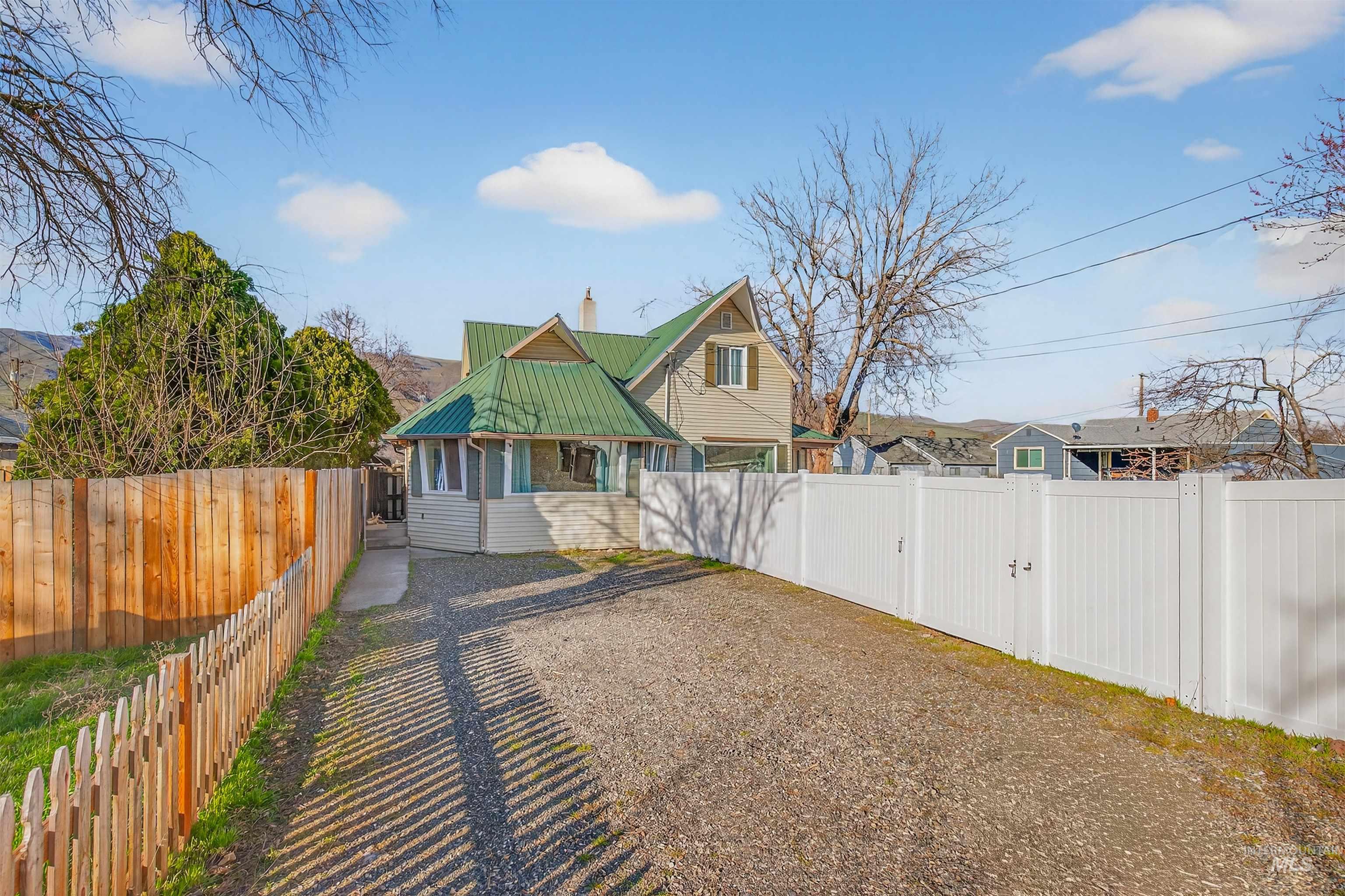 1266 Poplar Street Clarkston, WA 99403 - Photo 2 of 31 View of front of property featuring a metal roof, a fenced backyard, a chimney, and a residential view