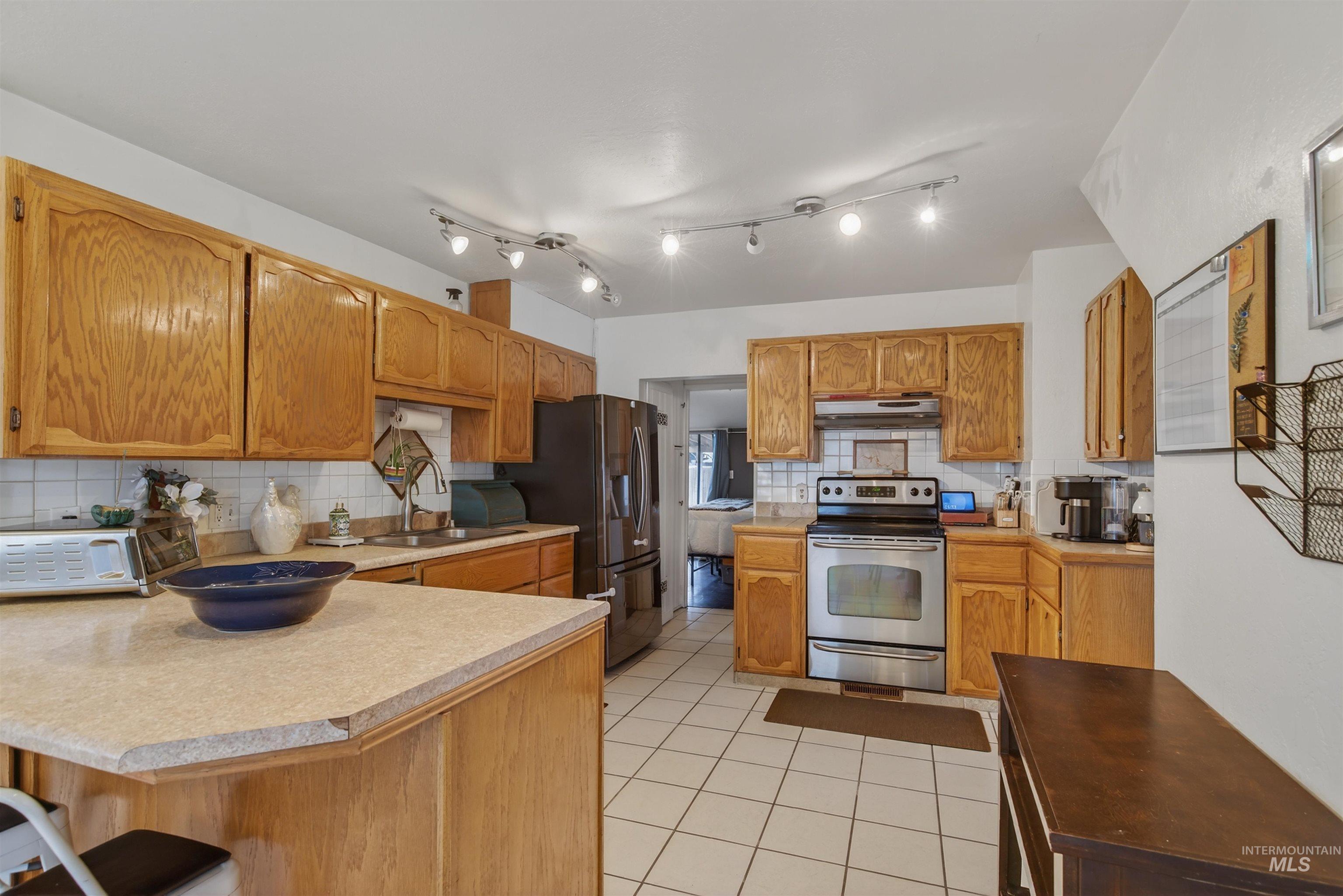 1266 Poplar Street Clarkston, WA 99403 - Photo 8 of 31 Kitchen with stainless steel appliances, a kitchen breakfast bar, a peninsula, light tile patterned floors, and decorative backsplash