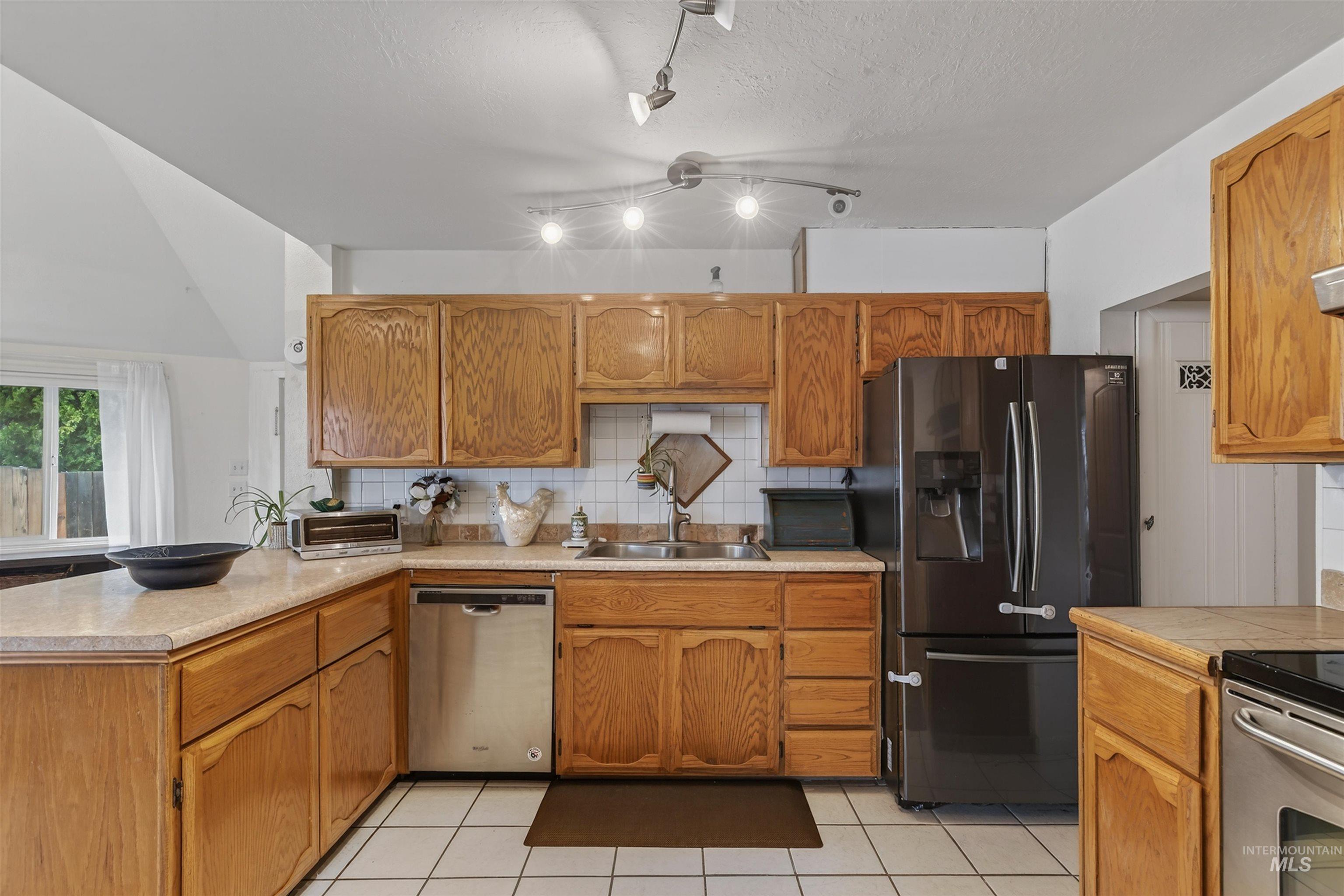 1266 Poplar Street Clarkston, WA 99403 - Photo 9 of 31 Kitchen with light countertops, stainless steel appliances, light tile patterned floors, and a peninsula