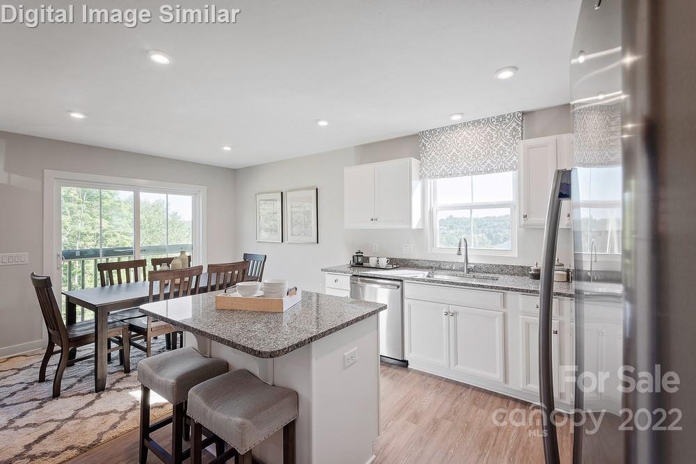325 Damask Drive, Unit 118 Lancaster, SC 29720 - Photo 3 of 12 a kitchen with granite countertop a sink and a stove top oven with wooden floor