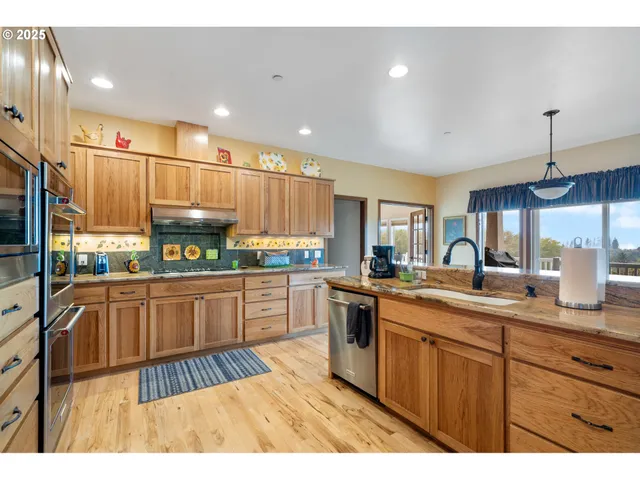 a kitchen with stainless steel appliances granite countertop a sink counter space cabinets and a large window