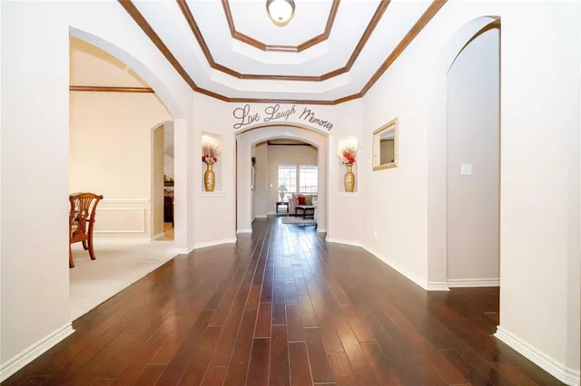 a view of a hallway with wooden floor table and chairs