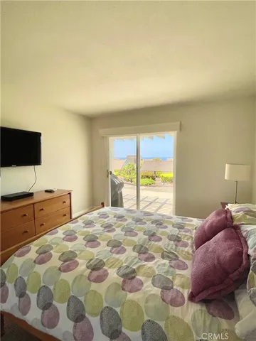 a bedroom with a large bed and a flat tv screen on dresser