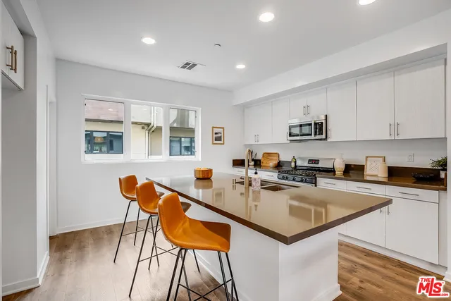 a kitchen with stainless steel appliances granite countertop a table chairs sink and cabinets