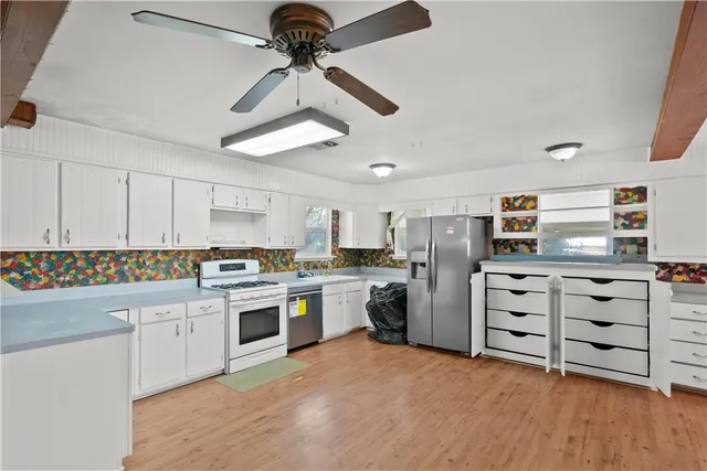 a kitchen with cabinets appliances and a ceiling fan