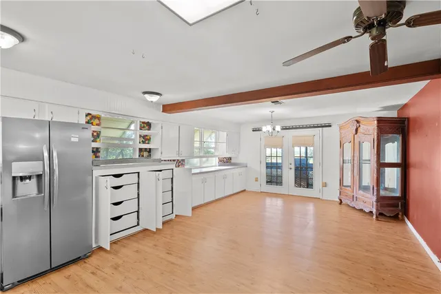 a large white kitchen with cabinets and wooden floor