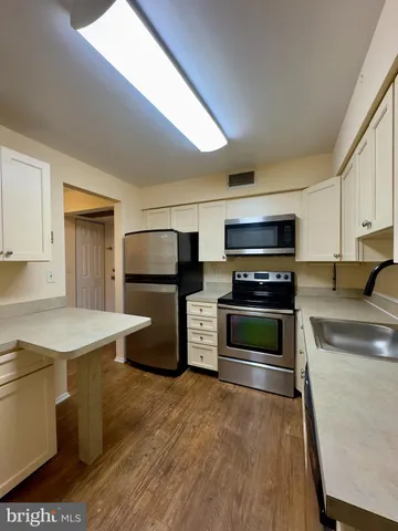a kitchen with stainless steel appliances a stove a refrigerator a sink a stove and white cabinets