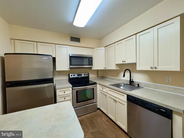 a kitchen with stainless steel appliances granite countertop a sink a stove a refrigerator a microwave and cabinets