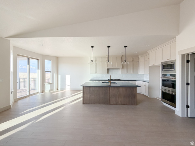 533 West S Temple Street, Unit 309 Tooele, UT 84074 - Photo 24 of 24 Kitchen with open floor plan, a kitchen island with sink, dark countertops, appliances with stainless steel finishes, and hanging light fixtures