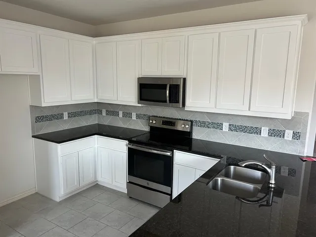 a kitchen with granite countertop white cabinets and stainless steel appliances
