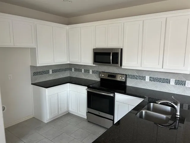 a kitchen with granite countertop white cabinets and stainless steel appliances
