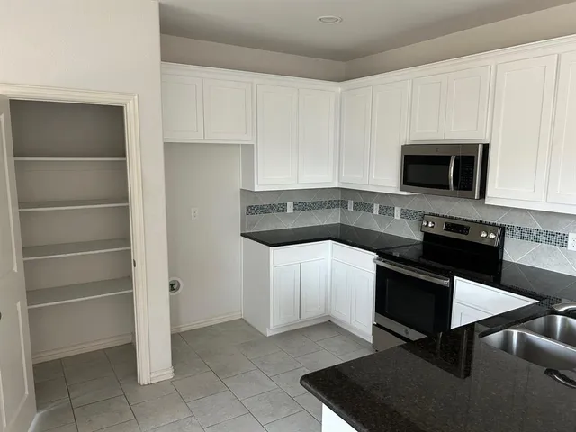 a kitchen with granite countertop a stove a microwave and a sink