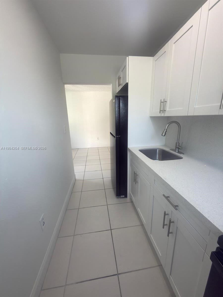 2622 Northwest 24th Street, Unit 1B Miami, FL 33142 - Photo 4 of 16 a kitchen with a sink a refrigerator and cabinets