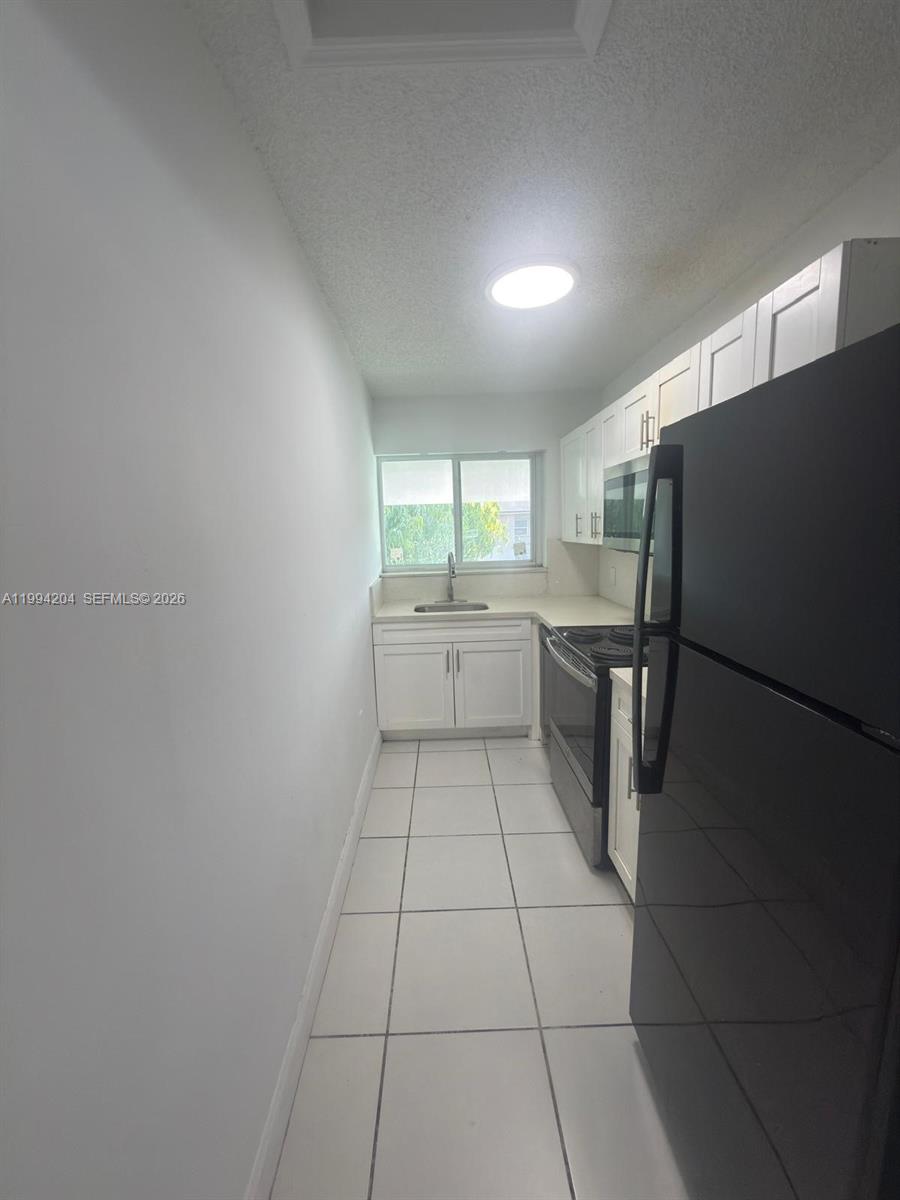 2622 Northwest 24th Street, Unit 1B Miami, FL 33142 - Photo 7 of 16 a kitchen with granite countertop a refrigerator and a stove top oven