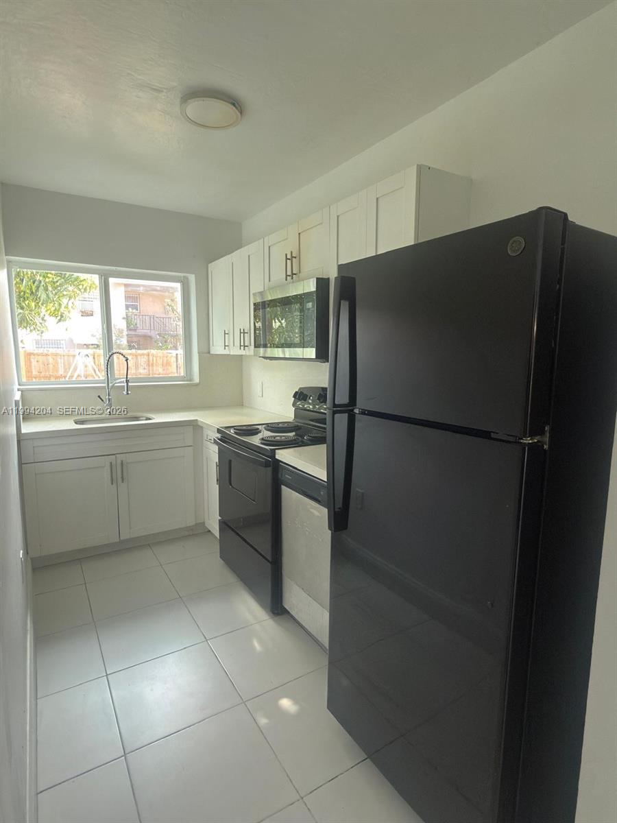 2622 Northwest 24th Street, Unit 1B Miami, FL 33142 - Photo 9 of 16 a kitchen with a refrigerator and a sink