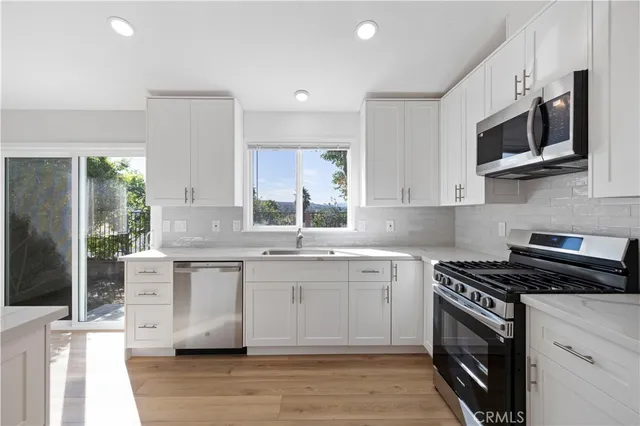 a kitchen with stainless steel appliances a sink a stove a microwave a sink and cabinets