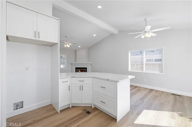 a kitchen with white cabinets and wooden floor