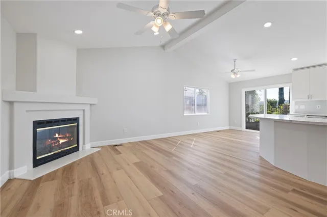 a view of a kitchen and an empty room with wooden floor fireplace