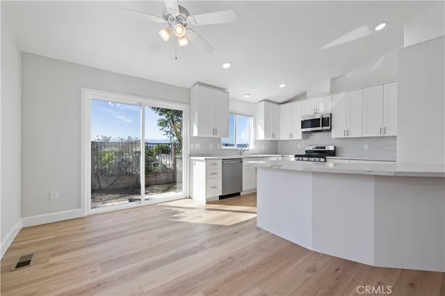 a kitchen with stainless steel appliances granite countertop a refrigerator a sink dishwasher a stove and white countertops with wooden floor