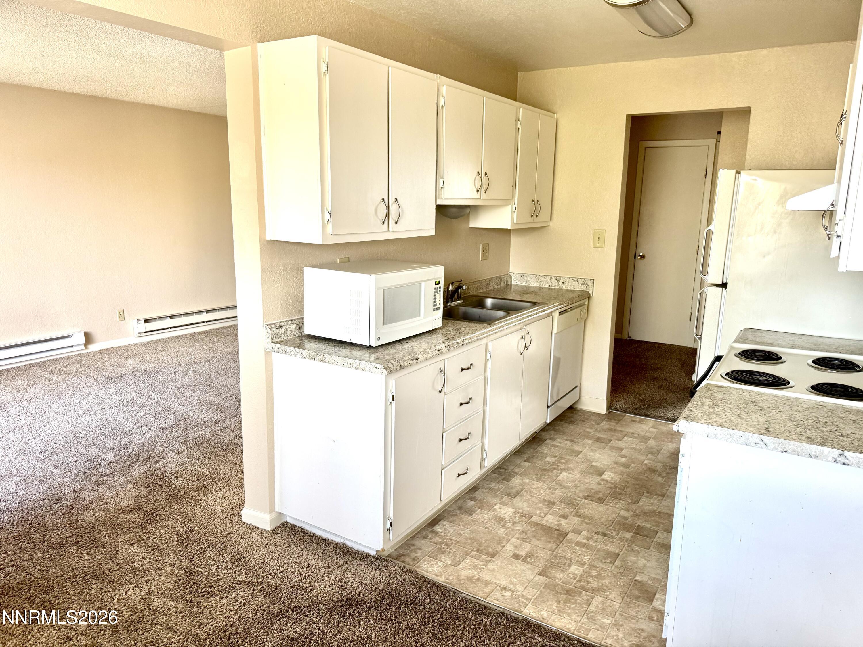 3949 Clear Acre Lane, Unit 284 Reno, NV 89512 - Photo 4 of 8 a kitchen with granite countertop white cabinets and white appliances