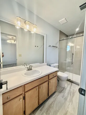 a bathroom with a double vanity sink toilet mirror and shower