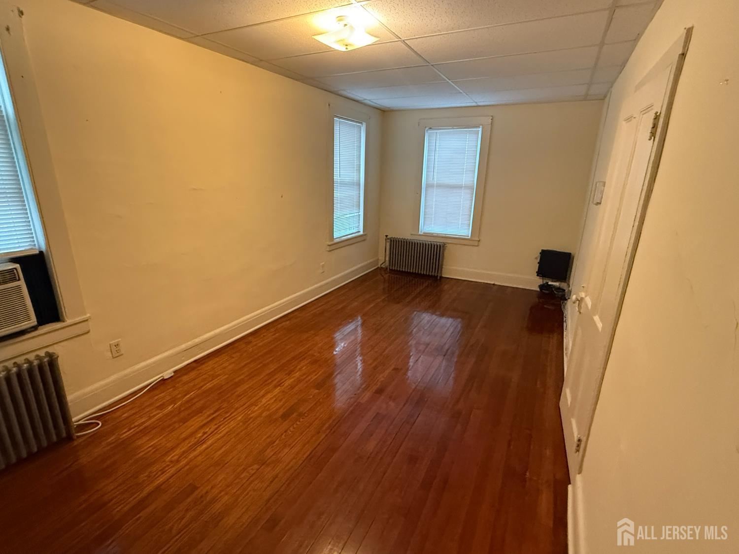 69 West Somerset Street, Unit D Raritan, NJ 08869 - Photo 5 of 12 a view of an empty room with wooden floor and a window