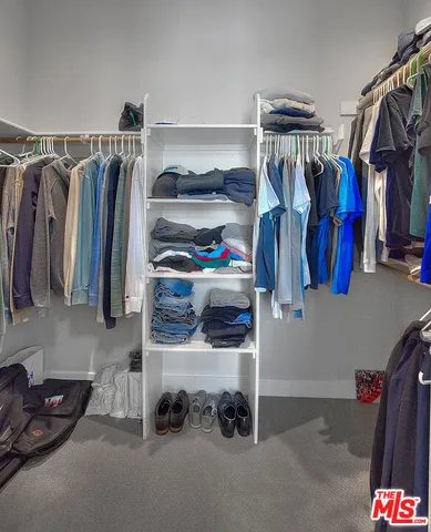 a view of walk in closet with clothes and shoes