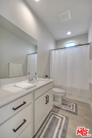 a bathroom with a granite countertop sink a toilet and a shower