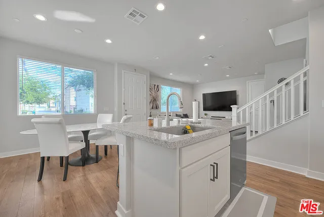 a kitchen with stainless steel appliances kitchen island granite countertop a sink and a wooden floor