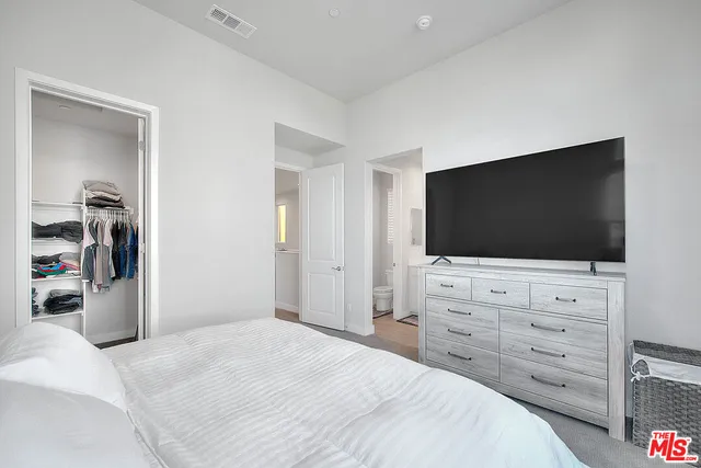a bedroom with a bed and a flat screen tv in white bedroom