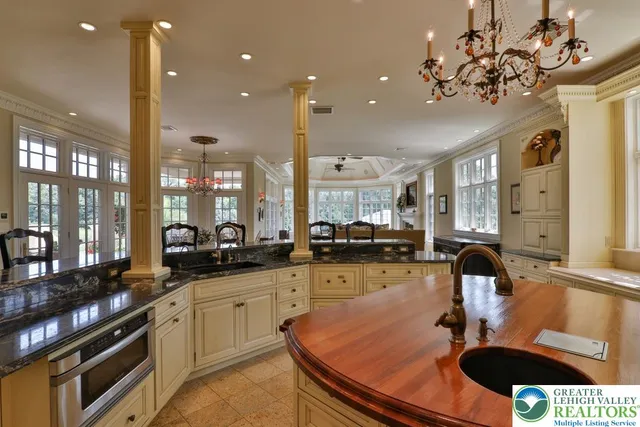 a dining room with furniture a chandelier and kitchen view