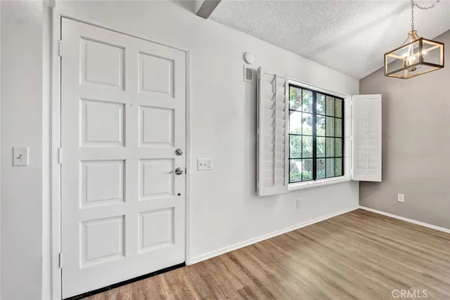 an empty room with wooden floor cabinet and windows