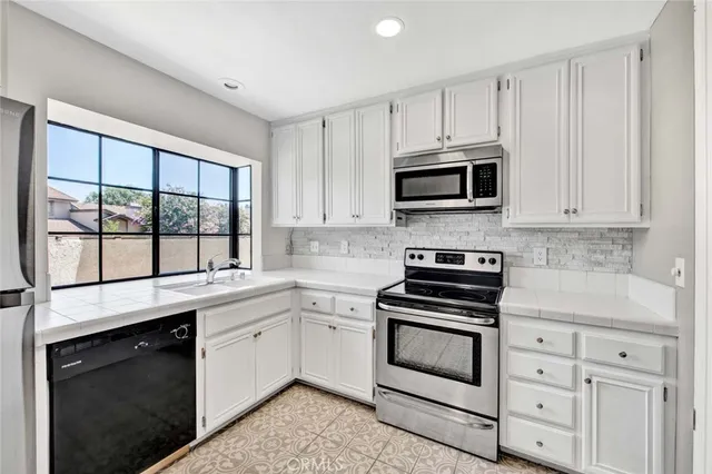 a kitchen with granite countertop white cabinets and a stove top oven