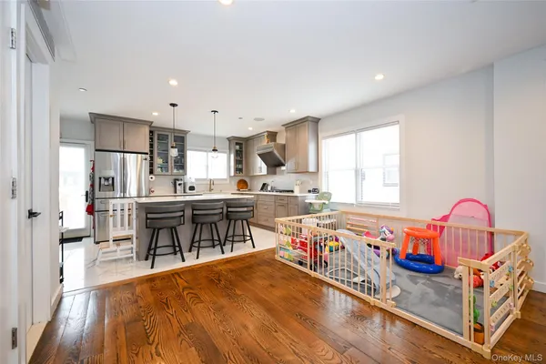 a kitchen with stainless steel appliances granite countertop a sink a stove a refrigerator and island with wooden floor