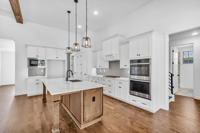 a view of an empty room with wooden floor and windows
