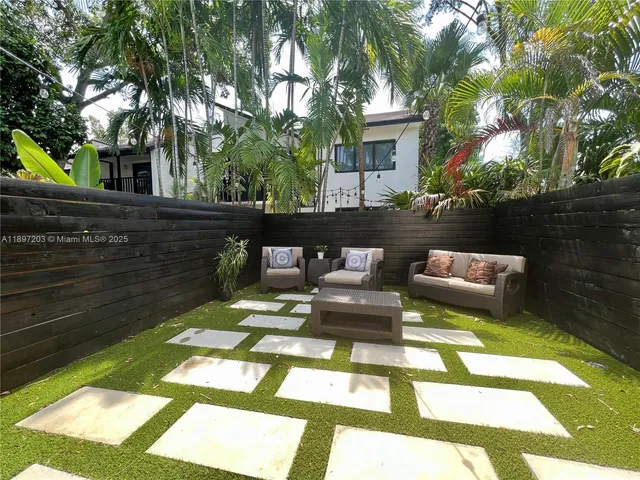a view of a patio with couches table and chairs and wooden fence