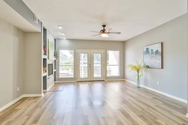a view of an empty room with window and wooden floor