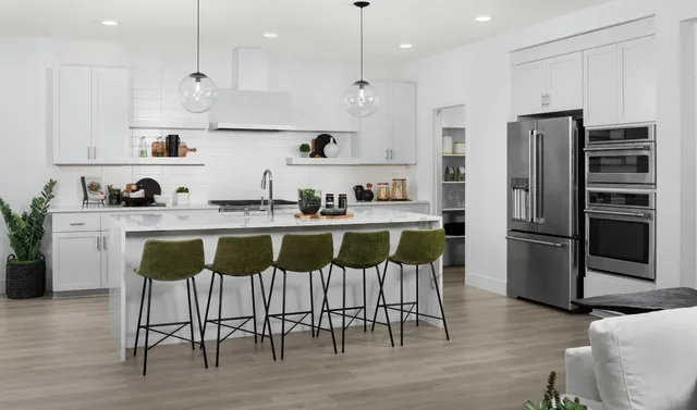 a kitchen with stainless steel appliances kitchen island granite countertop a table chairs and a refrigerator
