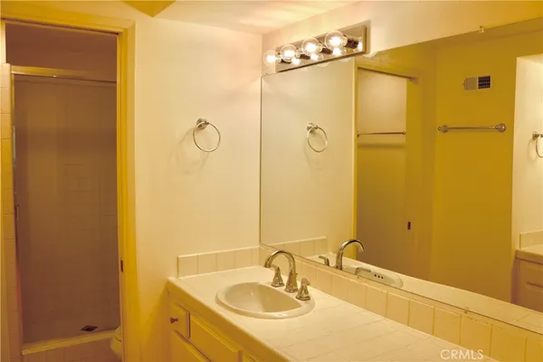a bathroom with a granite countertop shower sink and mirror