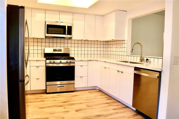 a kitchen with stainless steel appliances a stove microwave and sink