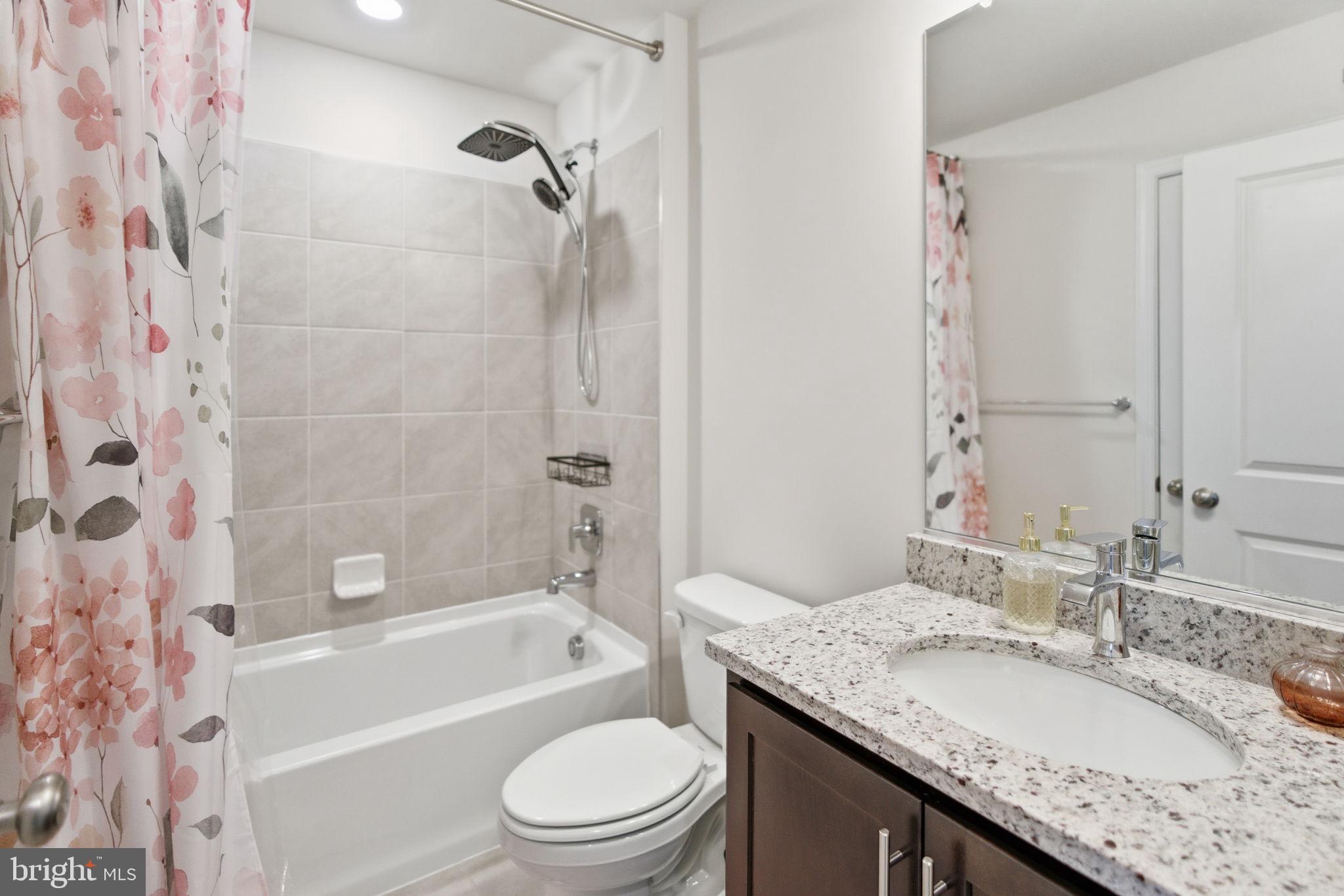 715 Courier Lane Frederick, MD 21701 - Photo 20 of 26 a bathroom with a granite countertop sink a toilet a mirror a bathtub and shower