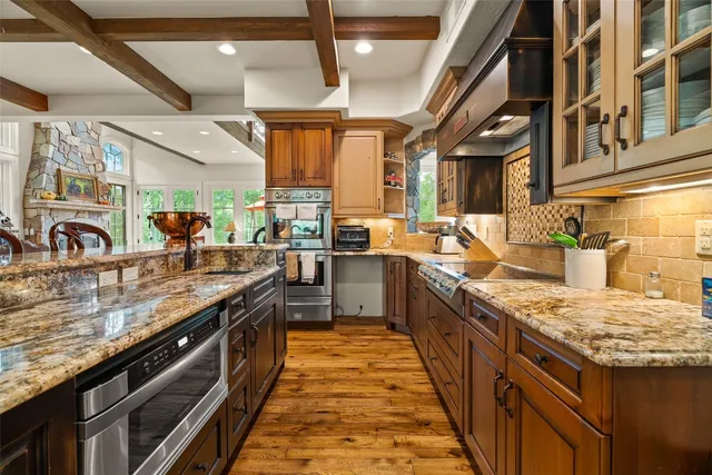 a large kitchen with stainless steel appliances granite countertop lots of counter space and a sink