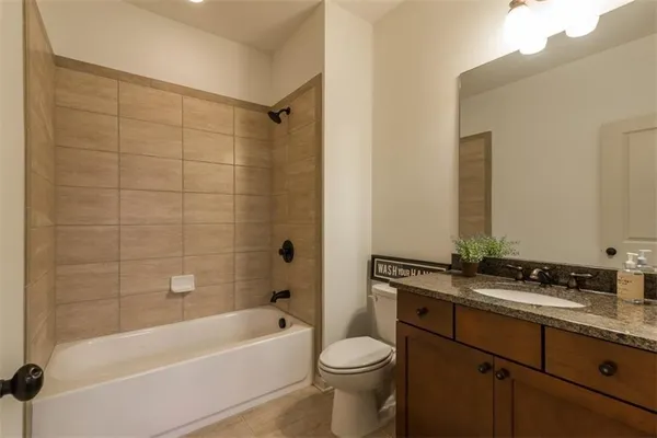 a bathroom with a granite countertop bathtub shower sink vanity and toilet