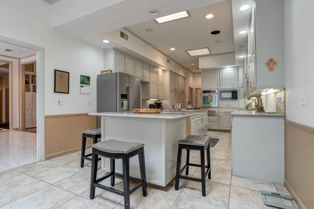 a kitchen with kitchen island granite countertop a sink cabinets and stainless steel appliances