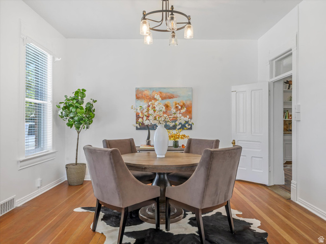 12825 South Fort Street Draper, UT 84020 - Photo 8 of 52 Dining area featuring wood-finish flooring, white baseboards, a window with blinds, a white paneled door, and a multi-bulb chandelier