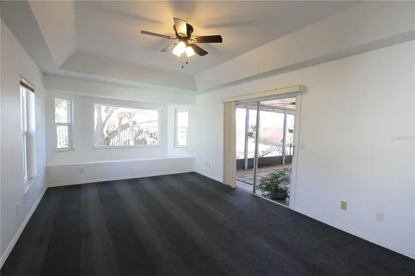 an empty room with wooden floor chandelier fan and windows