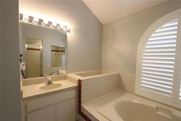 a bathroom with a tub sink and mirror