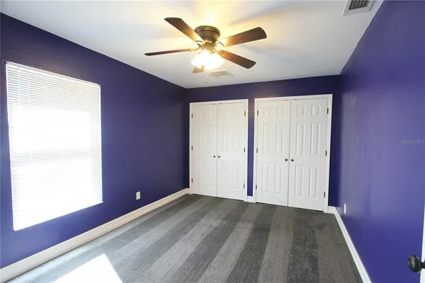 an empty room with closet and windows