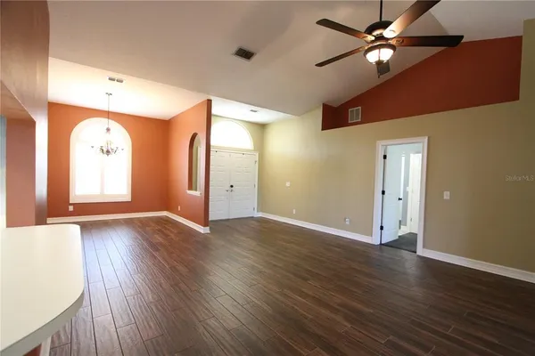 a view of an empty room with window and wooden floor