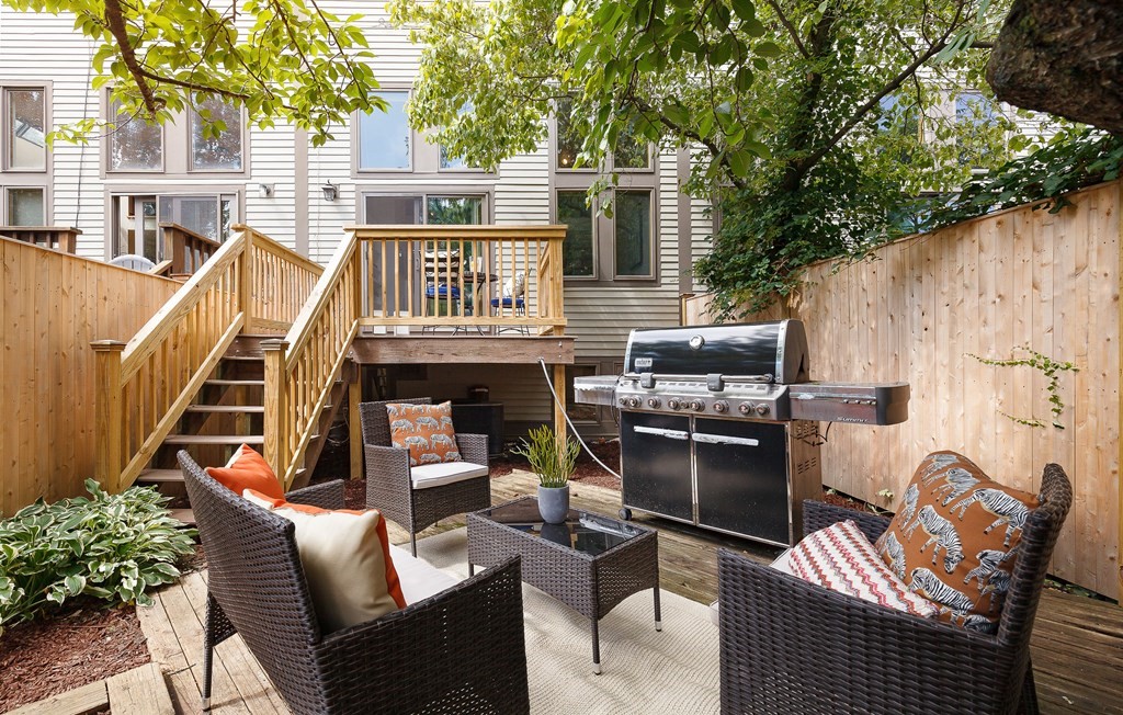 a view of a patio with couches table and chairs with wooden fence and plants